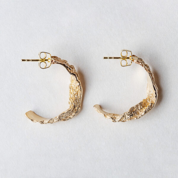 Handcrafted gold ocean wave earrings close-up showing flowing design