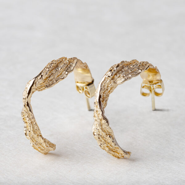 Handcrafted gold ocean wave earrings close-up showing flowing design