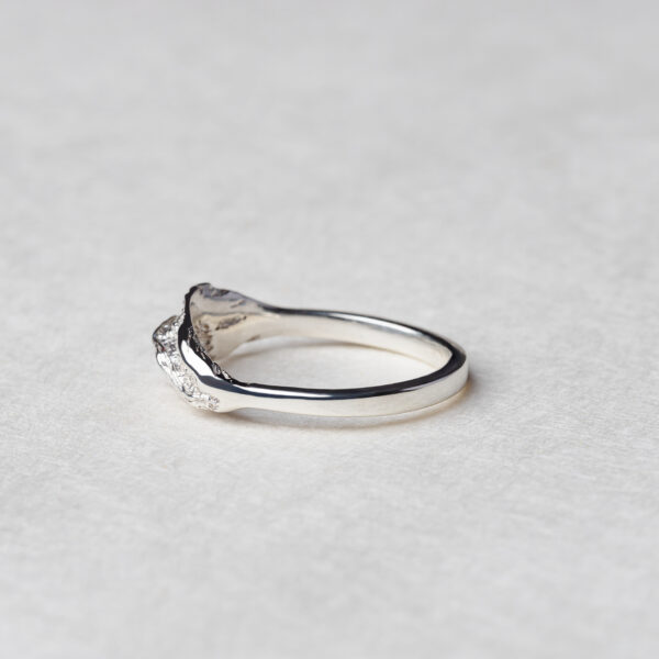 Ethically crafted silver ring with flowing, patterned strand resembling ocean waves"